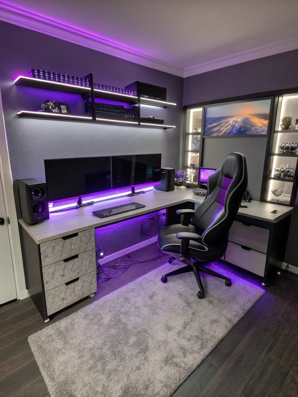 Luxurious 15'x17' gaming suite at twilight with rich purple, silver and black color scheme, featuring custom L-shaped desk with streaming gear, premium gaming chair, wall-mounted monitors, lit-up shelving for collectibles, and smart home integration, viewed from an elevated position.
